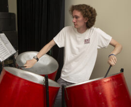 A college student performs on steel pans.
