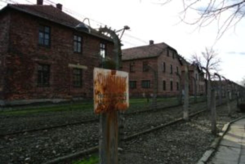 Rusty sign on barbed wire fence atAuschwitz