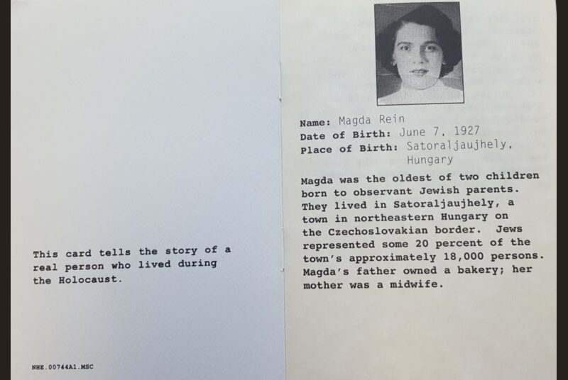 A card reading “This card tells the story of a real person who lived during the Holocaust. Name: Magda Rein. Date of Birth: June 7, 1927. Place of Birth: Satoraljaujhely, Hungary. Magda was the oldest of two parents. They lived in Satoraljaujhely, a town in northeastern Hungary on the Czechoslovakian border. Jews represented some 20 percent of the town’s approximately 18,000 persons. Magda’s father owned a bakery; her mother was a midwife.”