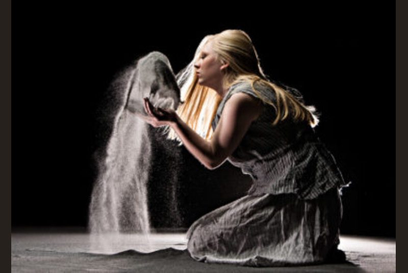 Performer on her knees tossing sand