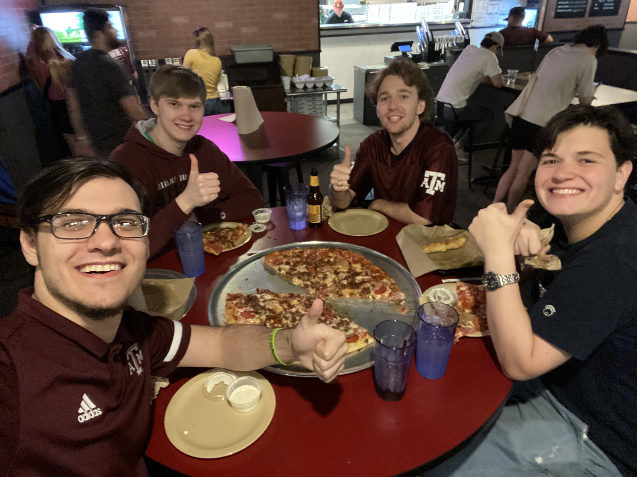Four members of a college Esports team smile at a pizza restaurant.