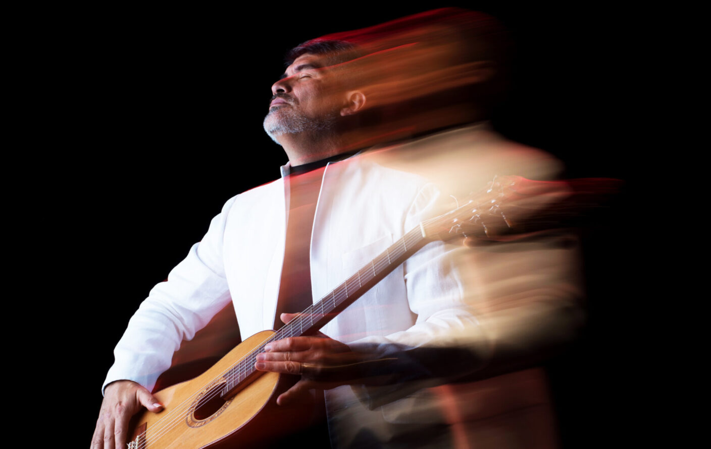 A musician lifts his head and closes his eyes as he plays the guitar