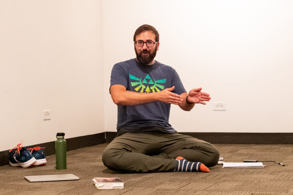 A man sits in a room with his legs criss cross. 