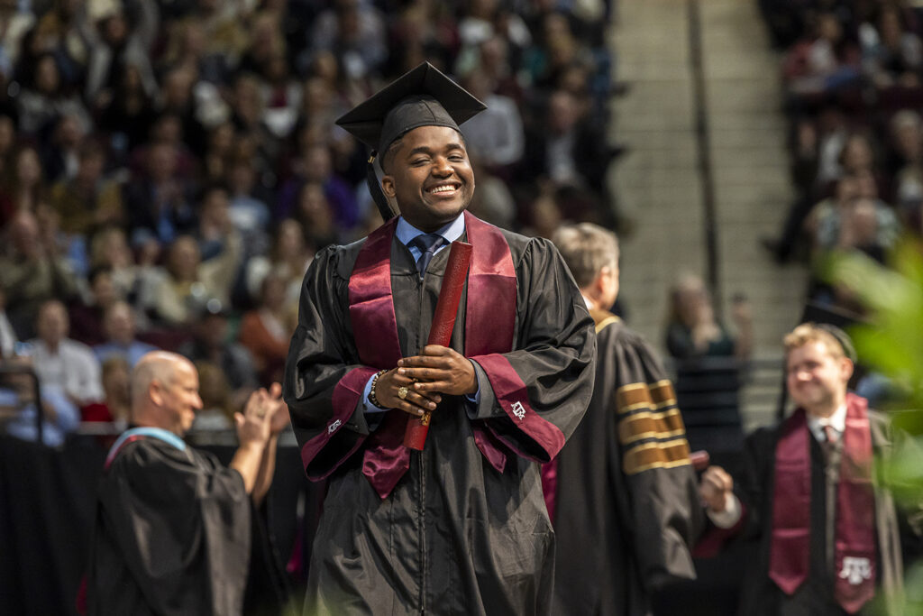 A grateful graduate holding his Maroon diploma tube