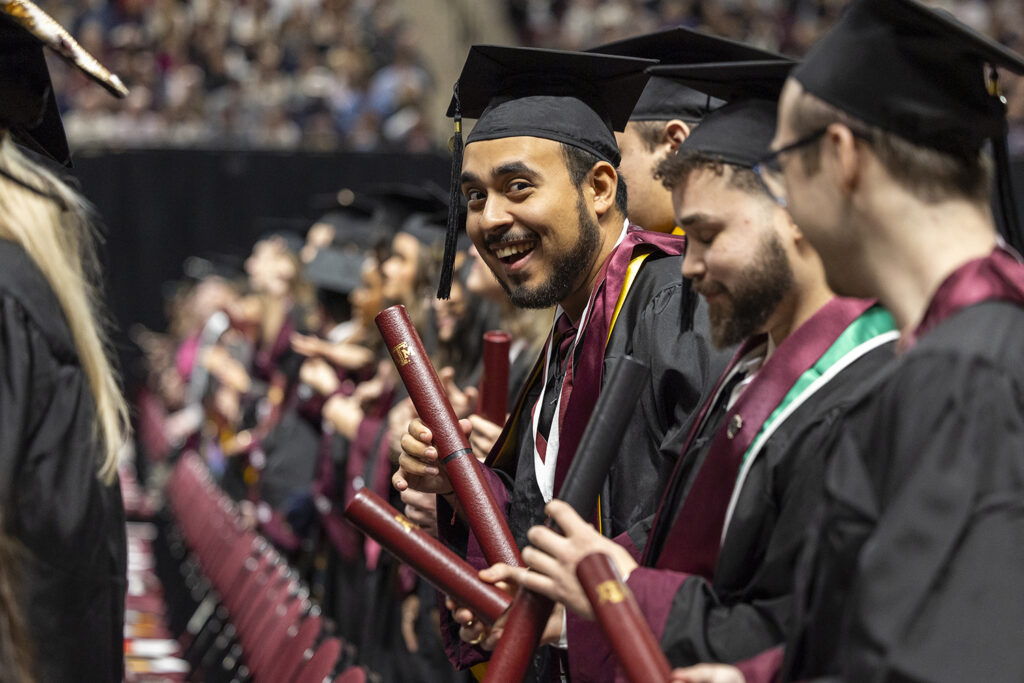 A college student with maroon tube clapping