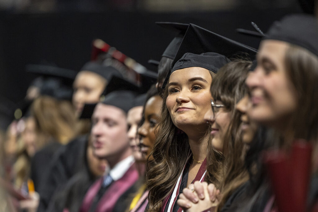 A student looks on as graduation pageantry proceeds  