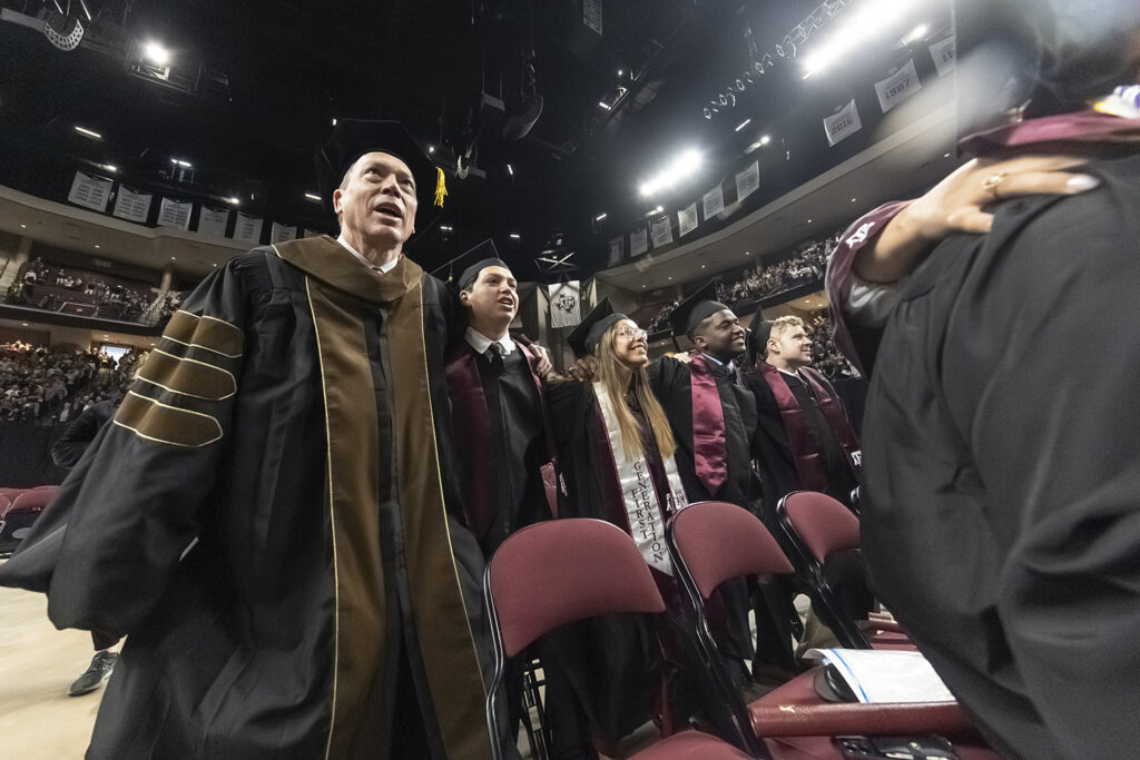 Dean singing the war hymn with graduates at texas A&m graduation 