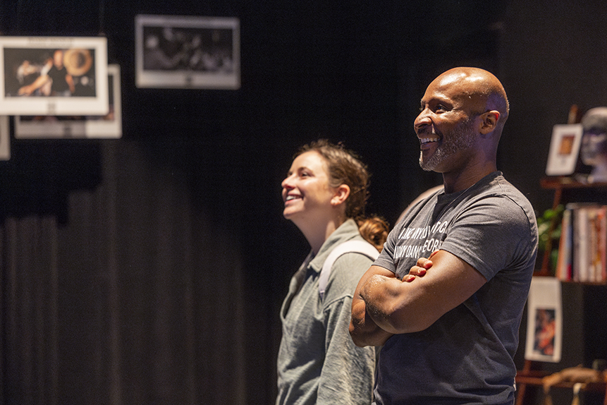 Two college dance professors smile as they watch a dance display at an interactive exhibit.