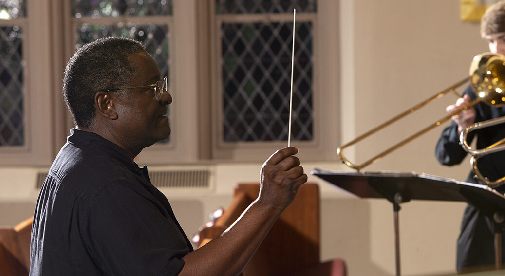 A music professor conducts a group of college students.