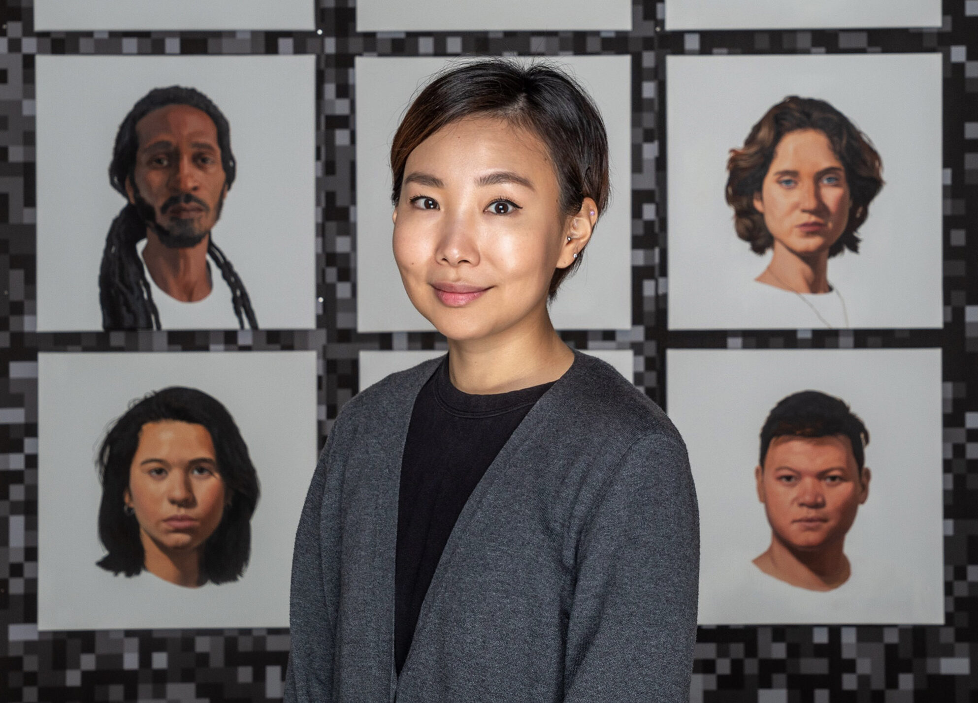 A college graduate student stands in front of a series of her paintings.