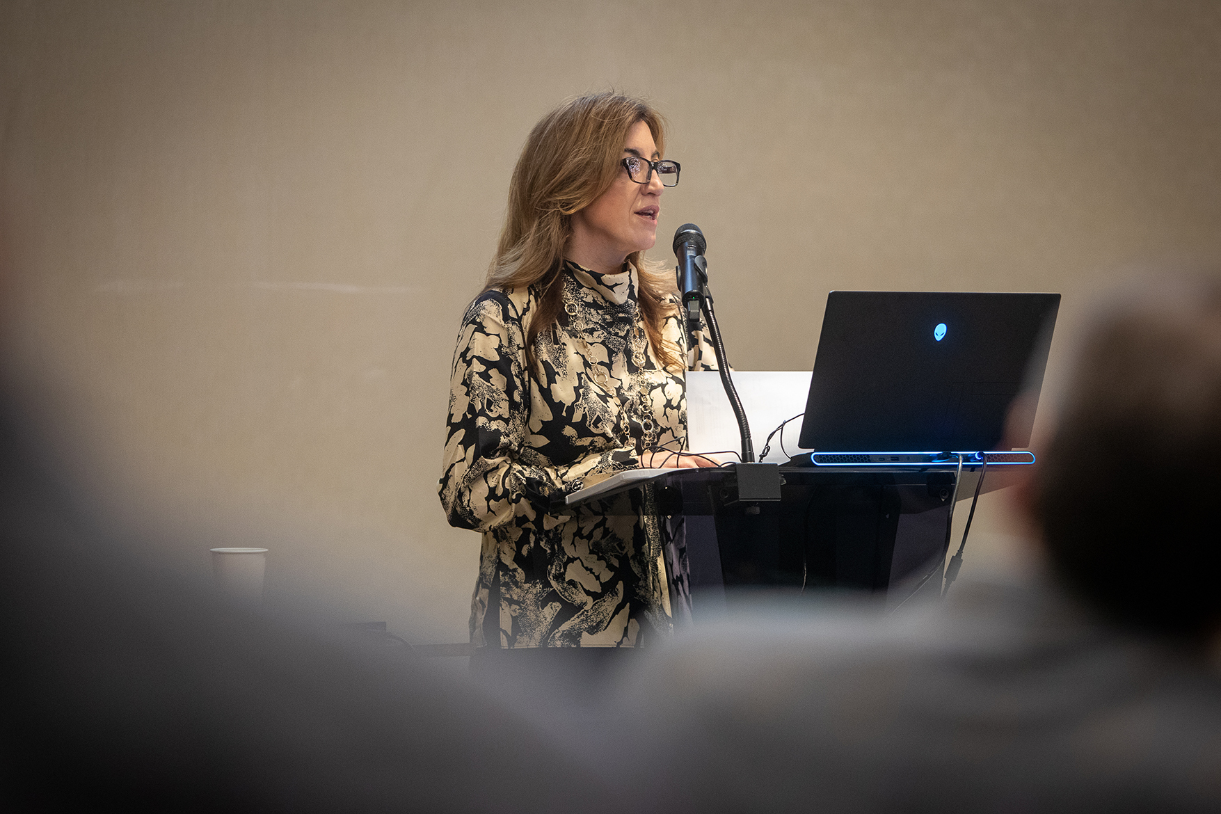 A woman speaks at a podium in a conference room.
