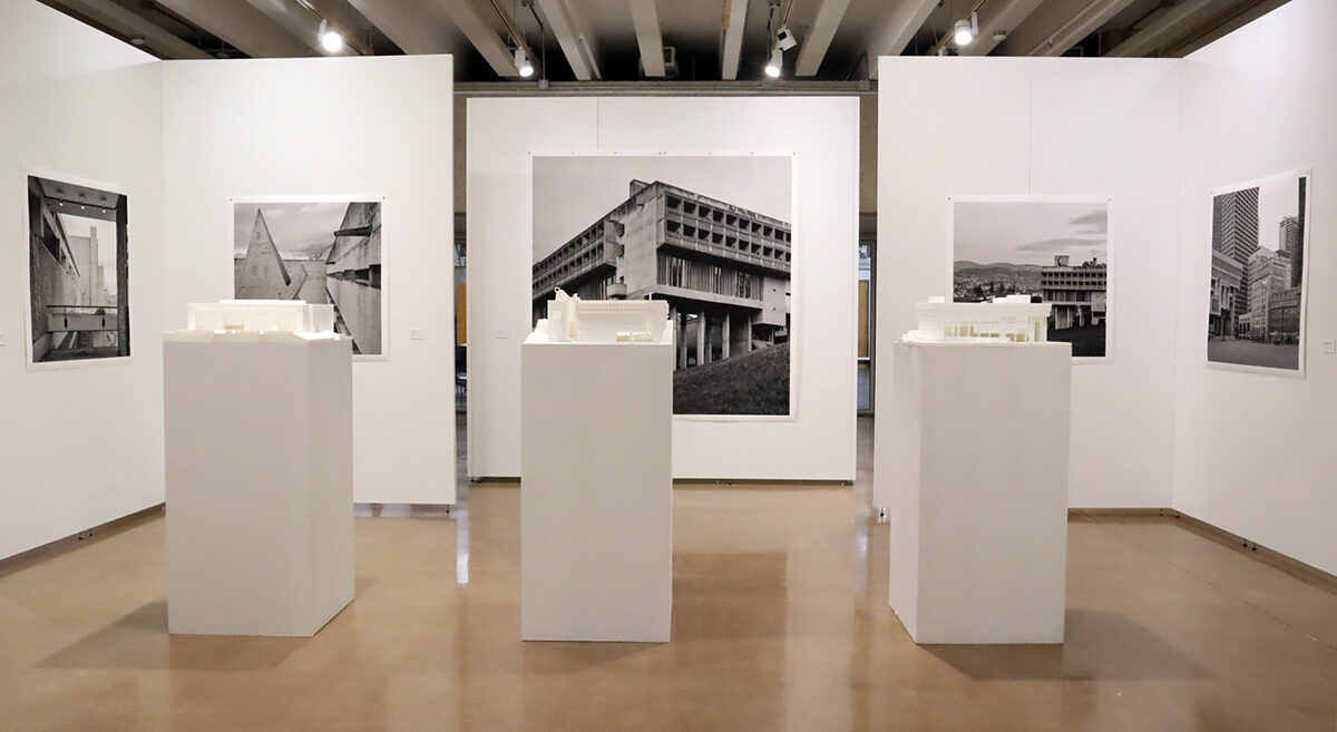 An art gallery features several black and white photographs of brutalist architecture examples.