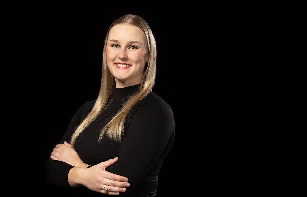 A college student smiles in front of a black background.