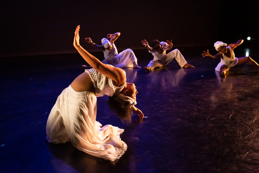 Dancers perform in a variety of poses on a stage.