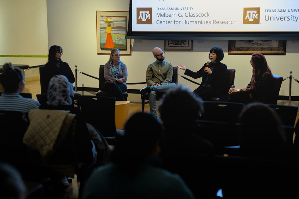 Five university professors are seated as they have a discussion in an art gallery event.