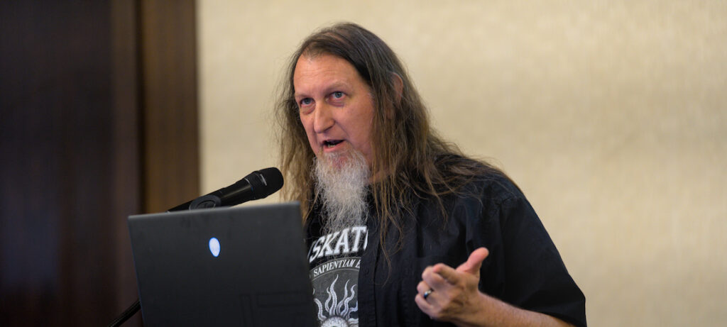 A university professor speaks a podium.