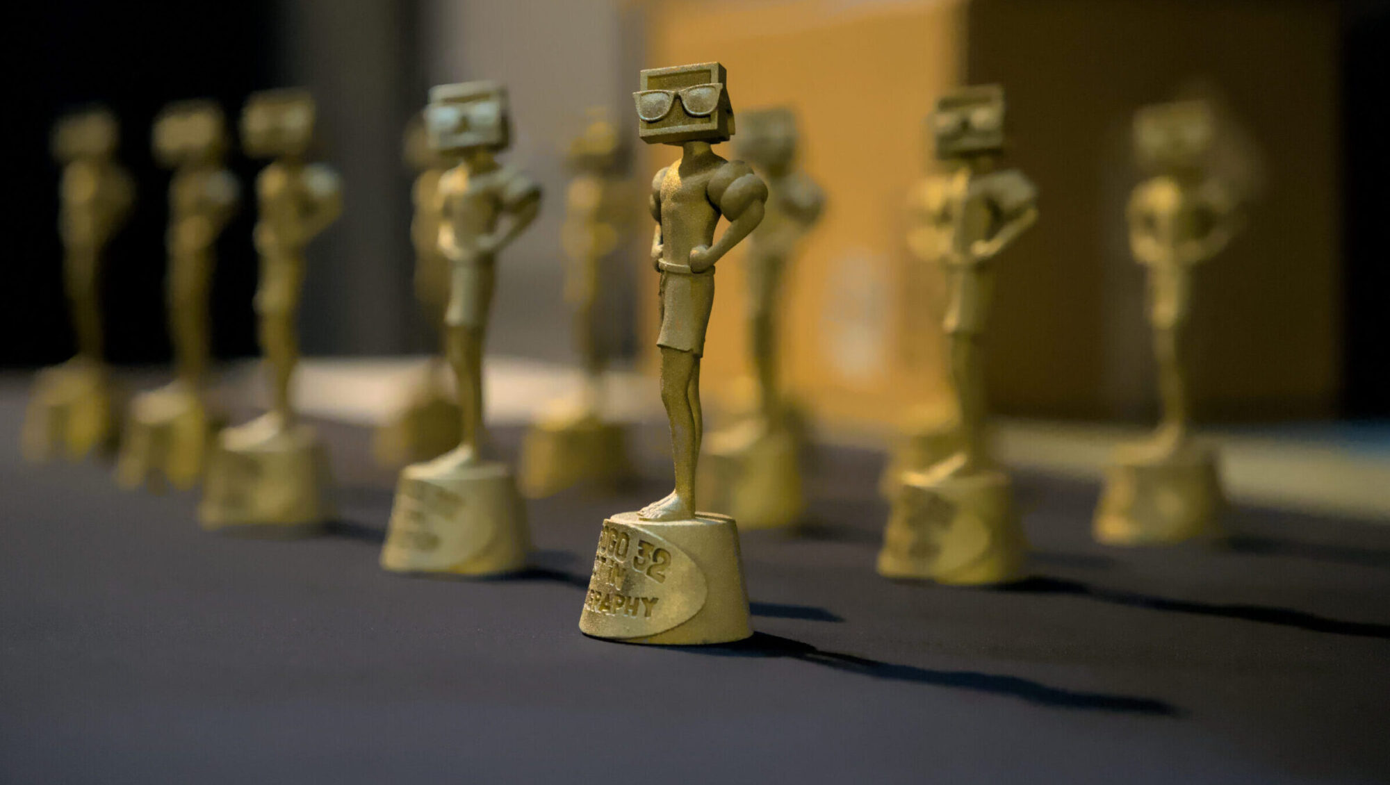 An array of gold statuettes featuring a TV for a head while wearing sunglasses known as a Vizzy.