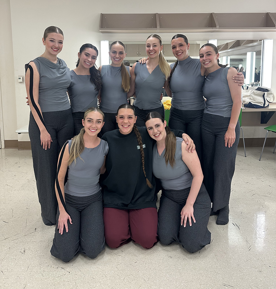 Nine college dance students smile as they pose for a picture.