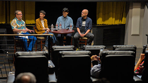 College professors discuss film onstage at a movie theater.