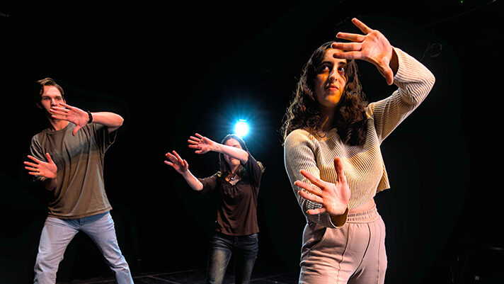 College students participate in a theatre exercise onstage.