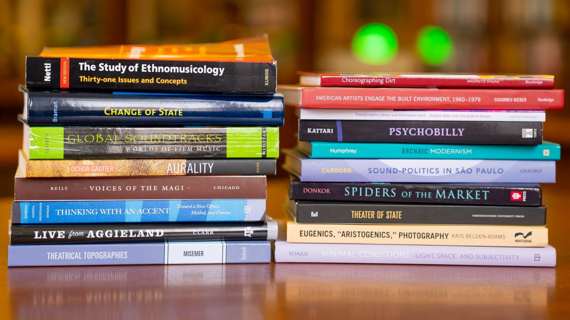 Two stacks of academic books sit on a table in a library.