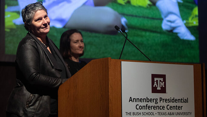 Two college dance professors give a presentation at a podium.
