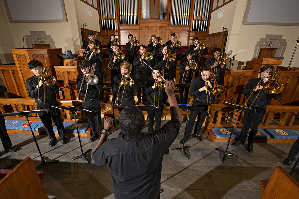 A choir of trombone players perform in a church.