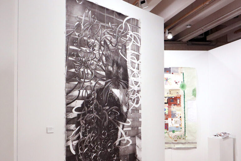 Several paintings hang in a gallery. The focus of the gallery images is the center with a black cat surrounded by swirls.