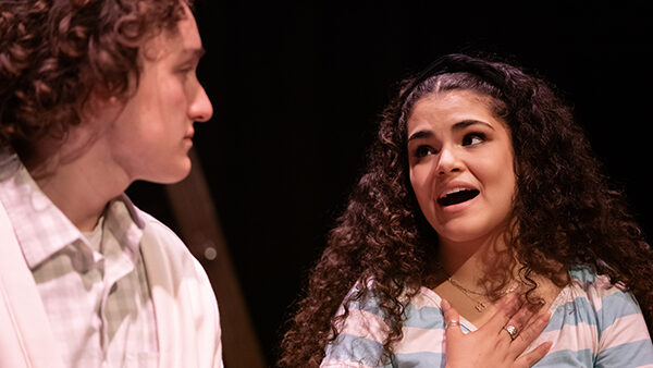 Two college students perform in a play in a black box theater.