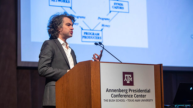 A college professor gives a presentation at a podium.