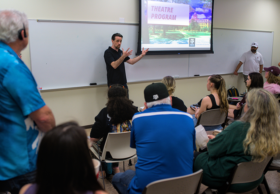 A faculty member from the theatre program gives a presentation in front of a room of people.