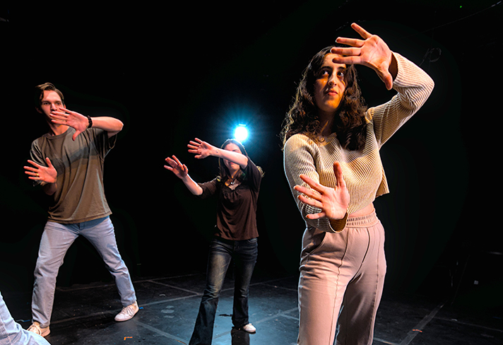 College students participate in a theatre exercise onstage.