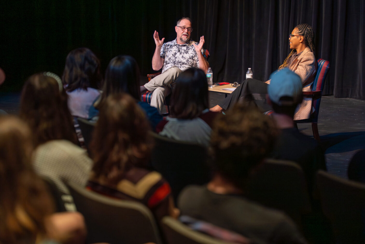 Students sit in front of Dave Maldonado and Mayet Andreasses in a Black Box Theatre. 