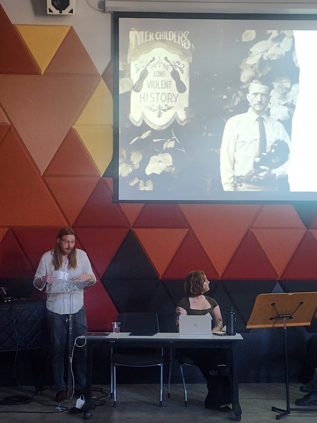 A university professor presents research on a power point slide as he stands at a podium. 